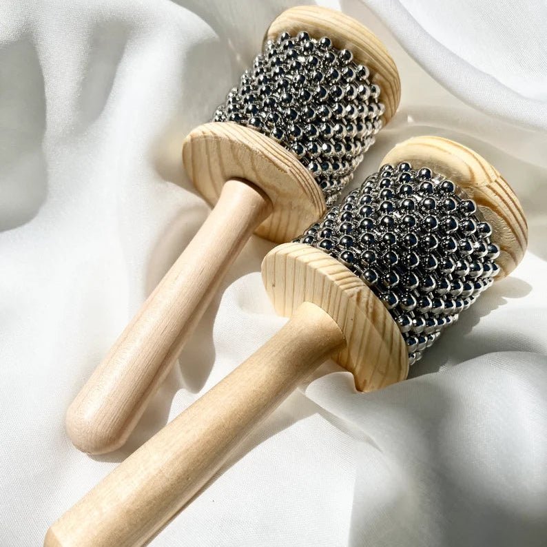 Two wooden cabasas on a white fabric background