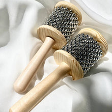Two wooden cabasas on a white fabric background