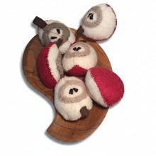 Six slices of felted apple on a wooden platter on a white background