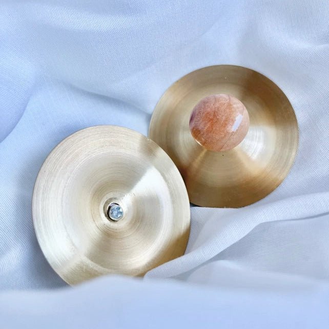 Two copper cymbals on a light fabric background
