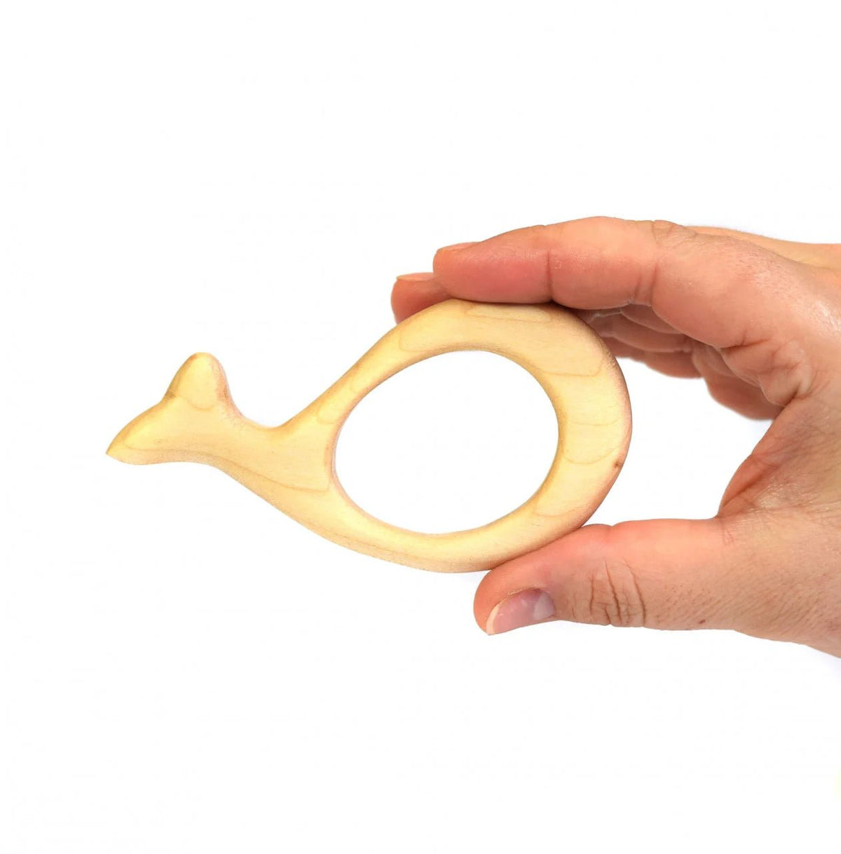 A hand holding a small, whale-shaped wooden teething toy against a plain white background.