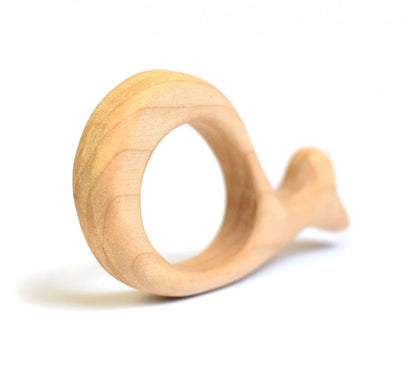 A light natural wood baby teether shaped like a whale, shown on a clean white background with a soft shadow.