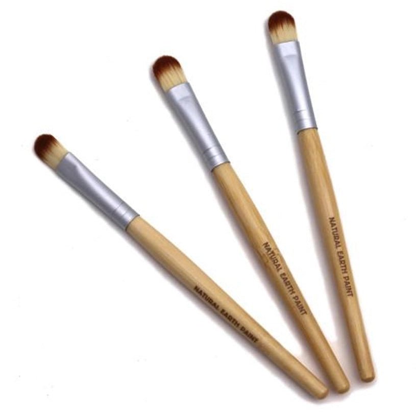 Three makeup brushes with wooden handles and silver ferrules on a white background