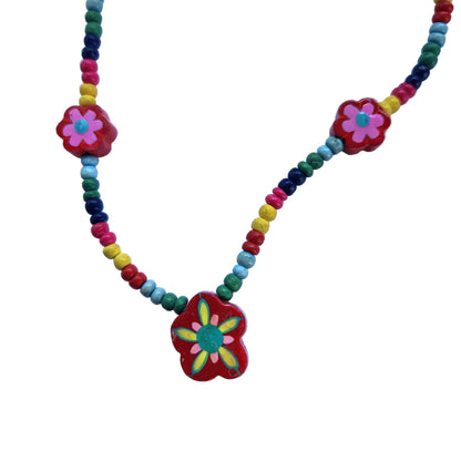 Close up of colorful beaded necklace with a flower pendant on a white background