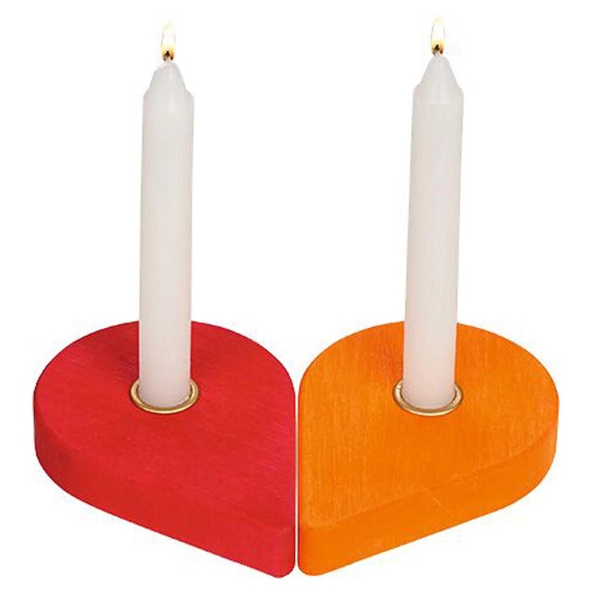 Two heart-shaped candle holders in red and orange, each holding a white taper candle with a small flame, shown on a plain white background.