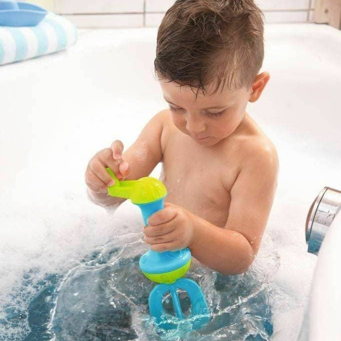 Child playing with bubble bath whisk in a tub full of bubbles