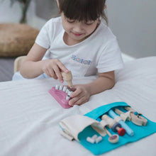 Child playing with wooden dentist set on a bed
