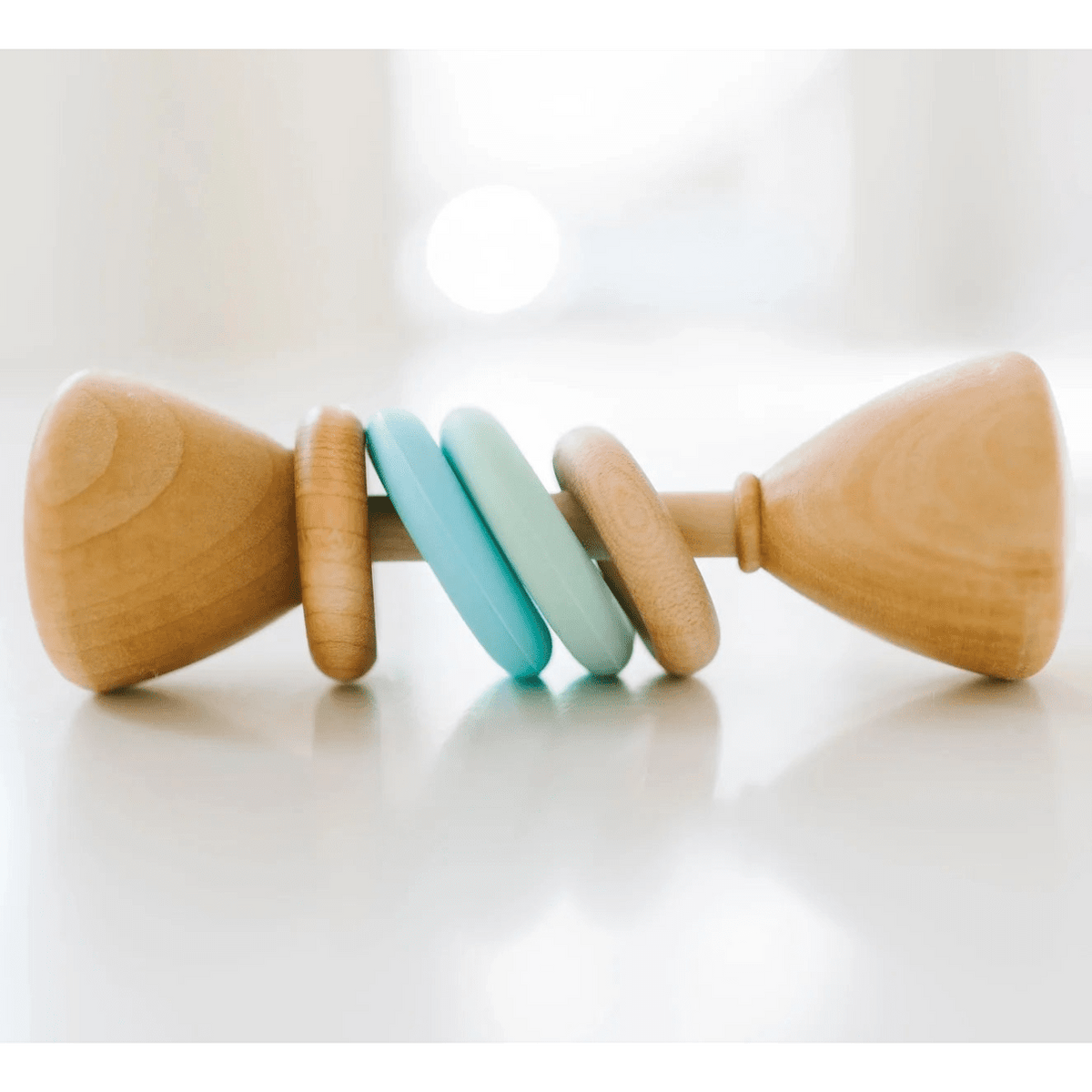 Wooden baby rattle with colorful blue rings on a white surface