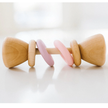 Wooden baby rattle with pink and purple accents on a white background