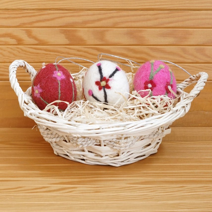 Decorative Easter eggs with floral patterns in a woven basket on a wooden surface
