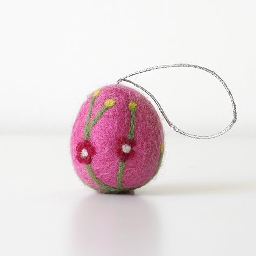 Pink felted ornament with floral designs on a white background