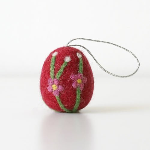 Red felted egg ornament with floral design and string on a white background