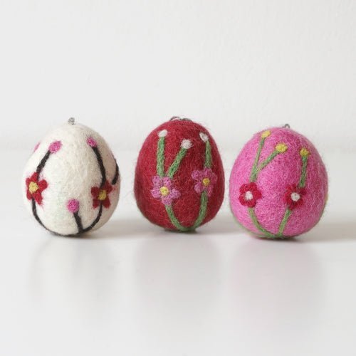 Three felted eggs with floral patterns on a white background