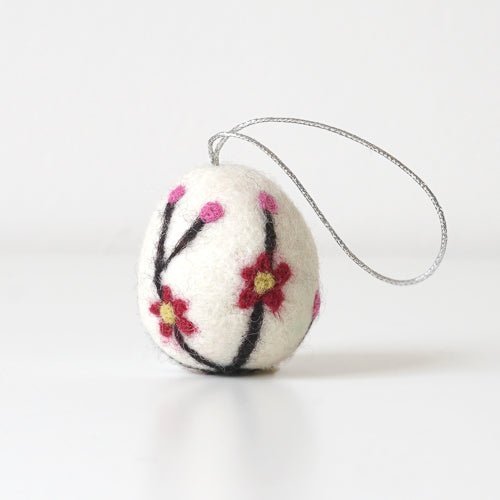 White decorative felt egg ornament with floral design on a white background