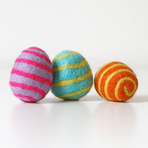 Three colorful striped felted eggs on a white background