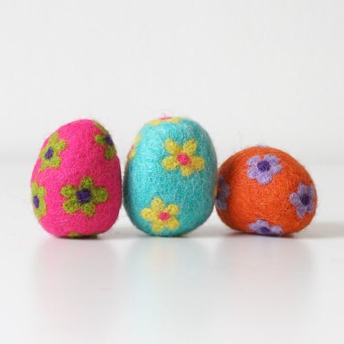 Three colorful felted eggs with floral patterns on a white background