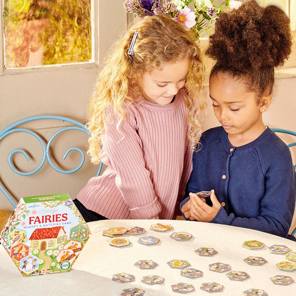 Two children playing with a 'Fairies' board game on a table.