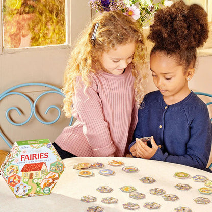 Two children playing with a 'Fairies' board game on a table.