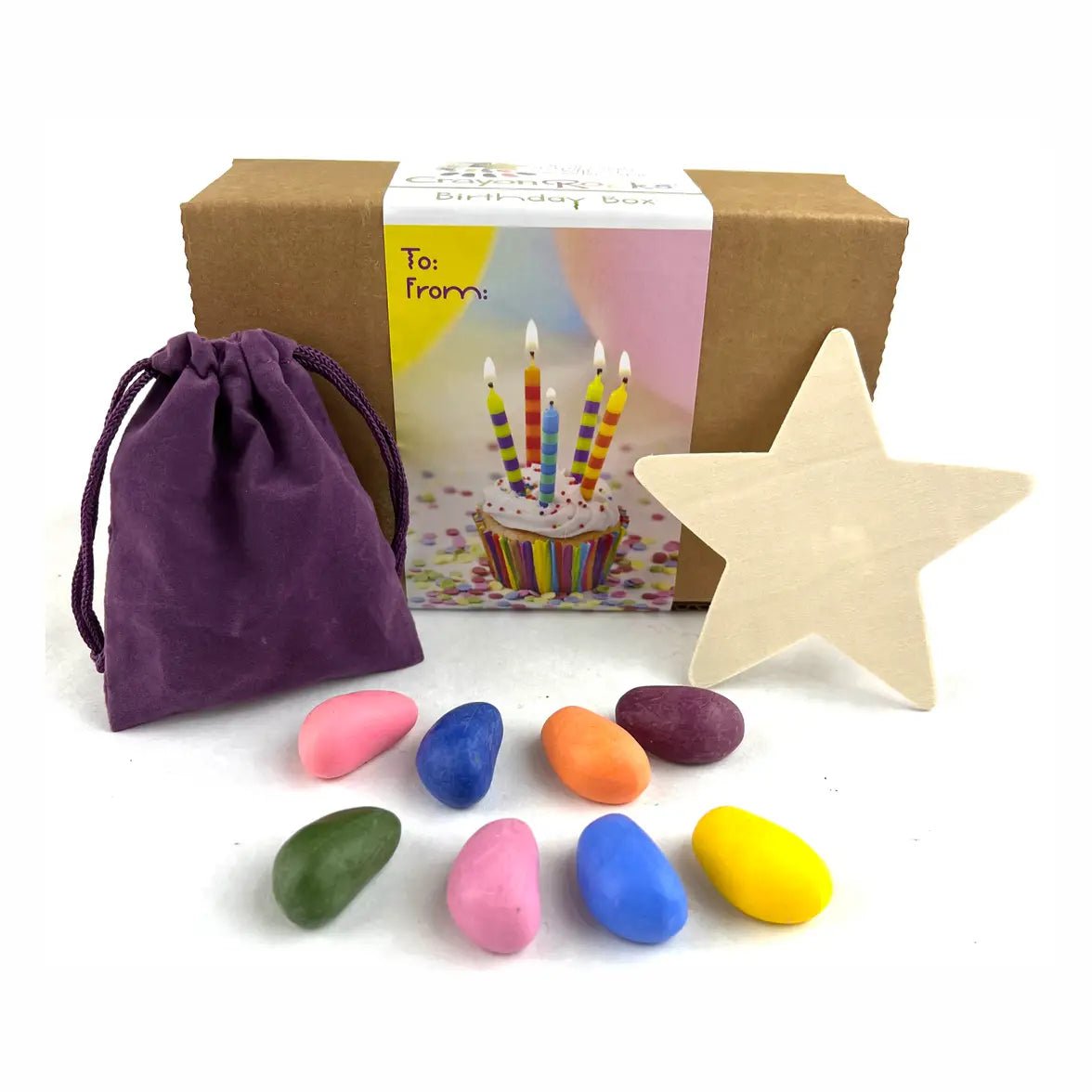 To/From box with rock-shaped crayons next to a purple velvet bag and a wooden star on a white background