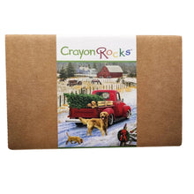 Crayon Rocks branded box with vintage-style art of a red pickup truck with a Christmas tree in the bed driving down a snowy road surrounded by dogs.