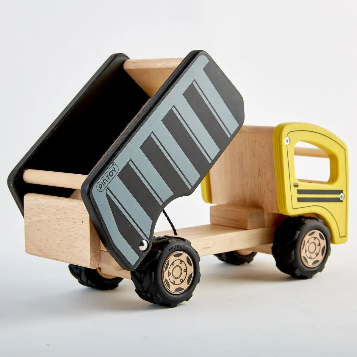 A wooden toy dump truck with a natural wood body, a yellow cab, and a black and gray striped dump bed, shown on a clean white background.