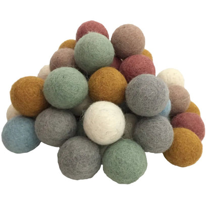 49 felt balls in earth tones arranged in a pile on a white background