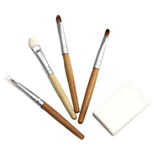 Four makeup applicators with wooden handles and one makeup sponge on a white background