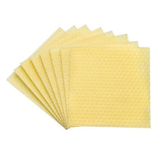 Stack of yellow honeycomb wax sheets on a white background