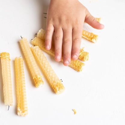 Hand interacting with honeycomb candles on a white surface