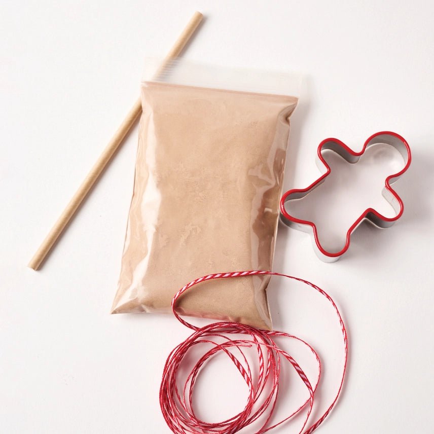 Gingerbread salt-dough, red string, and gingerbread man cookie cutter on a white background