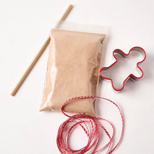 Gingerbread salt-dough, red string, and gingerbread man cookie cutter on a white background