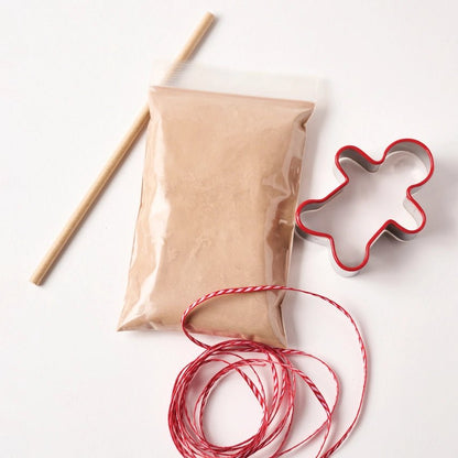 Gingerbread salt-dough, red string, and gingerbread man cookie cutter on a white background