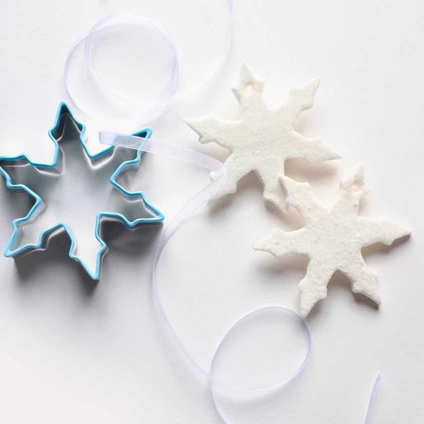 Snowflake cookie cutter and decorative snowflakes on a white background