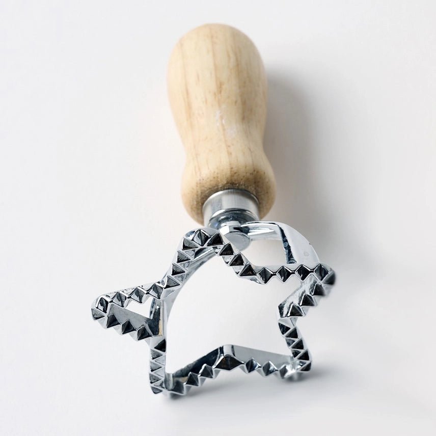 Metal star-shaped cookie cutter with wooden handle on a white background