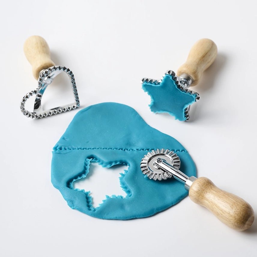 Cookie cutters with star and heart shapes on a piece of blue fondant.