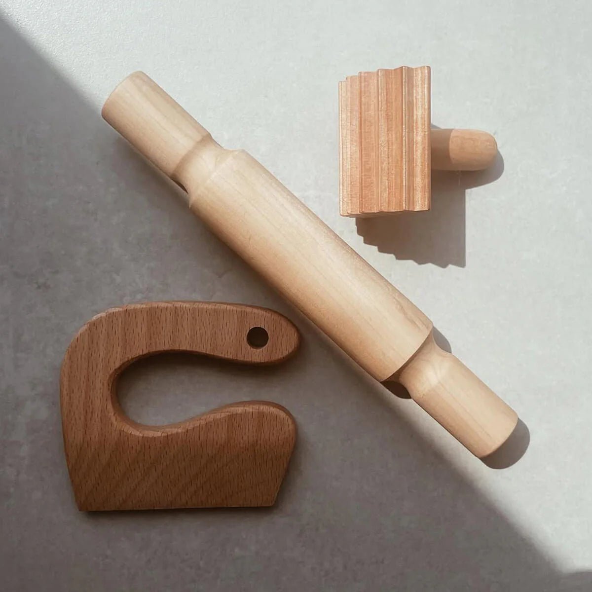 Wooden eco-dough tools including a rolling pin, knife, and textured roller.