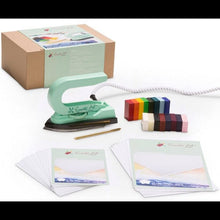 Green Encaustic Art iron, colorful blocks, and stationery items on a white background