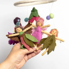 Hand holding three needle felted fairies attached to a mobile against a white background