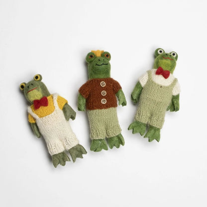 Three felted frog toys dressed in different outfits on a white background