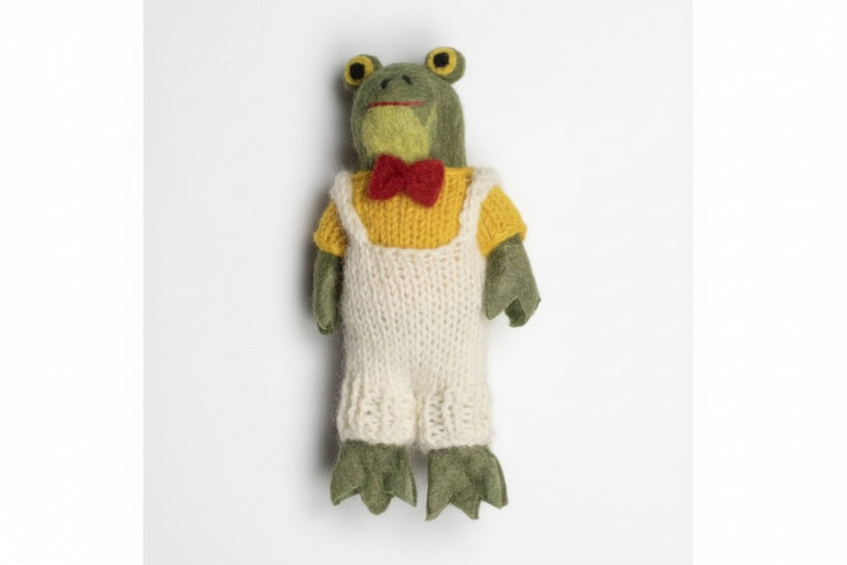 Knitted frog toy with a yellow sweater and red bow tie on a white background