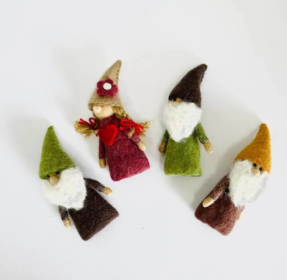 Four small gnome finger puppets with different hairstyles and outfits on a white background