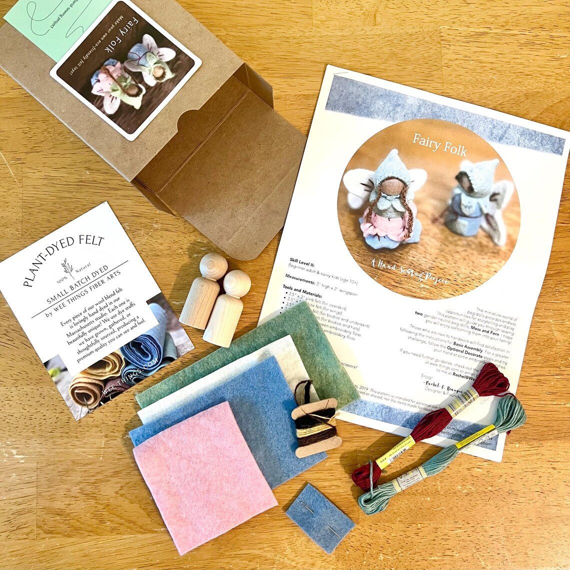 Crafting kit with felt pieces, wooden tools, and instructions on a wooden surface