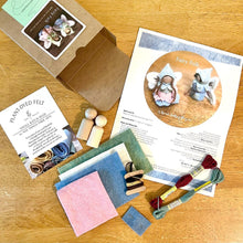 Crafting kit with felt pieces, wooden tools, and instructions on a wooden surface