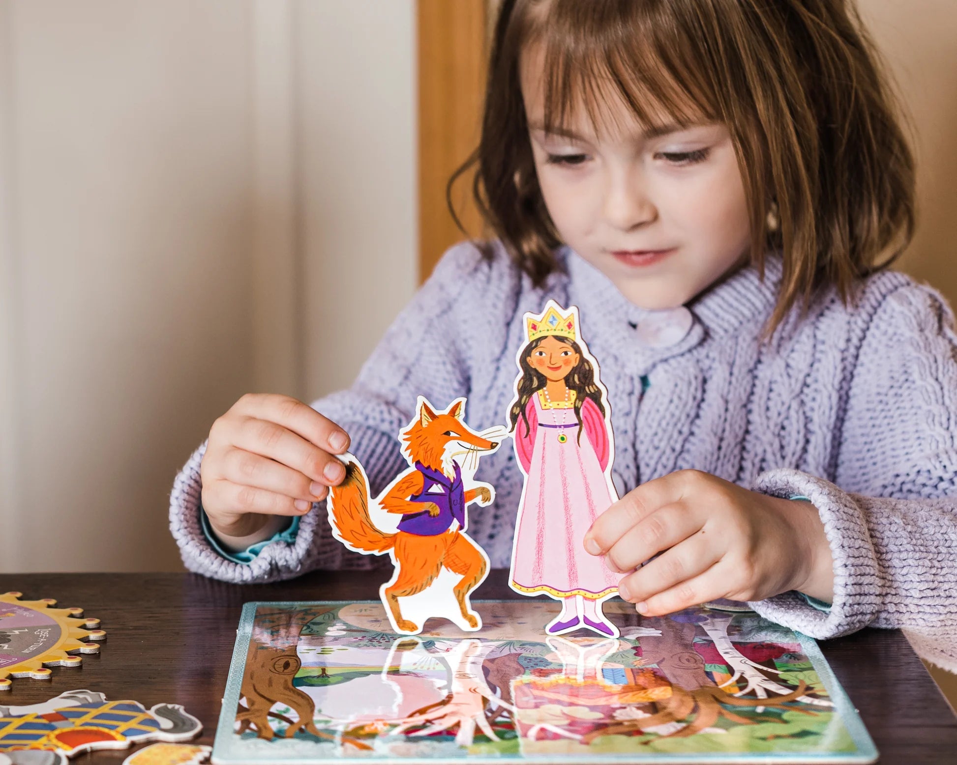 Child playing with a princess and fox paper cutout on a table