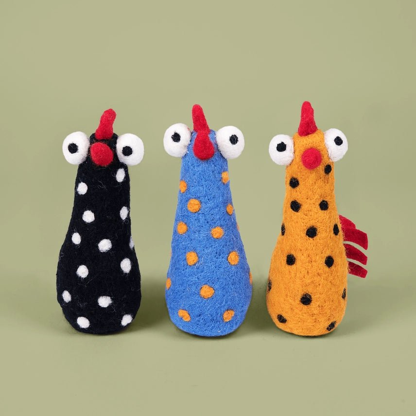 Three colorful felted chicken-shaped toys on a green background