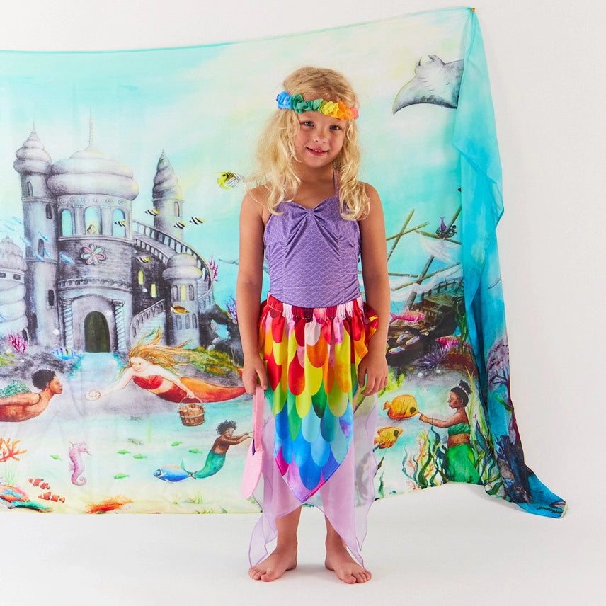 Girl wearing rainbow colored mermaid skirt against a underwater themed silk