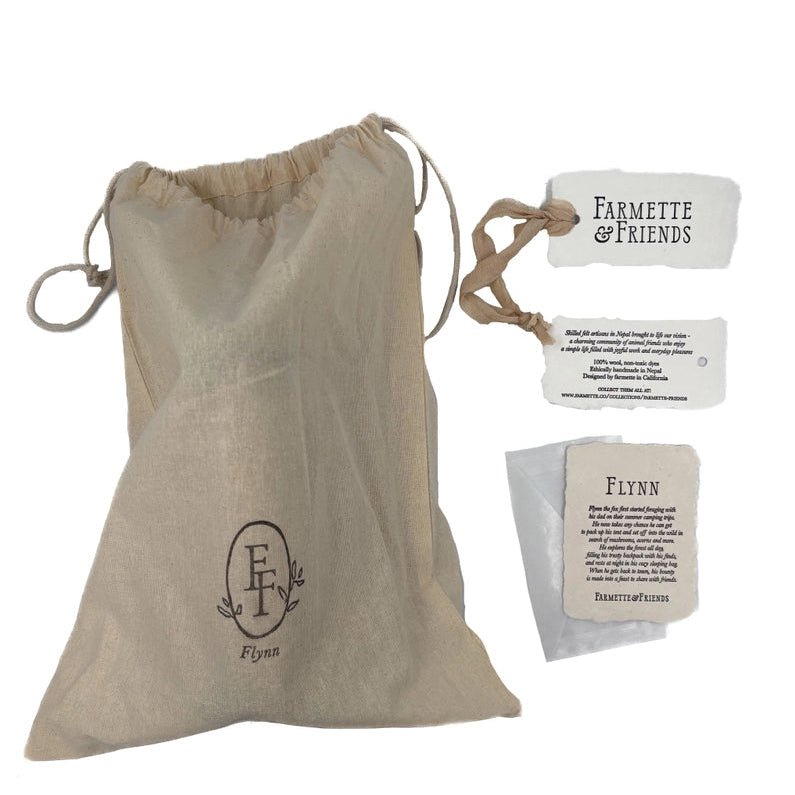 A beige linen drawstring pouch with a custom monogram logo, shown alongside branded paper tags reading 'Farmette & Friends' and 'Flynn'.