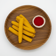 Felted french fries and bowl of ketchup on a wooden plate on a white background