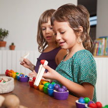 Children sorting differently colored wooden acorns into wooden bowls of the same colors