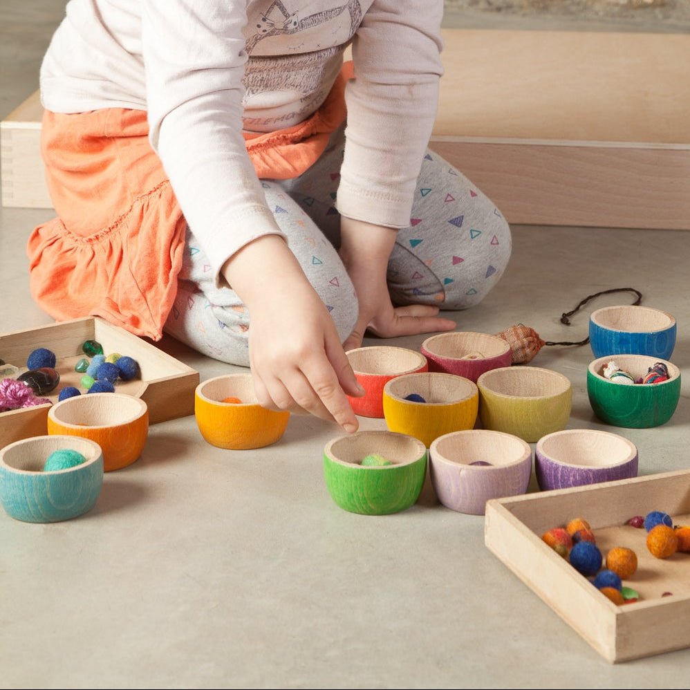 Child sorting objects in 12 differently colored bowls in a play setting
